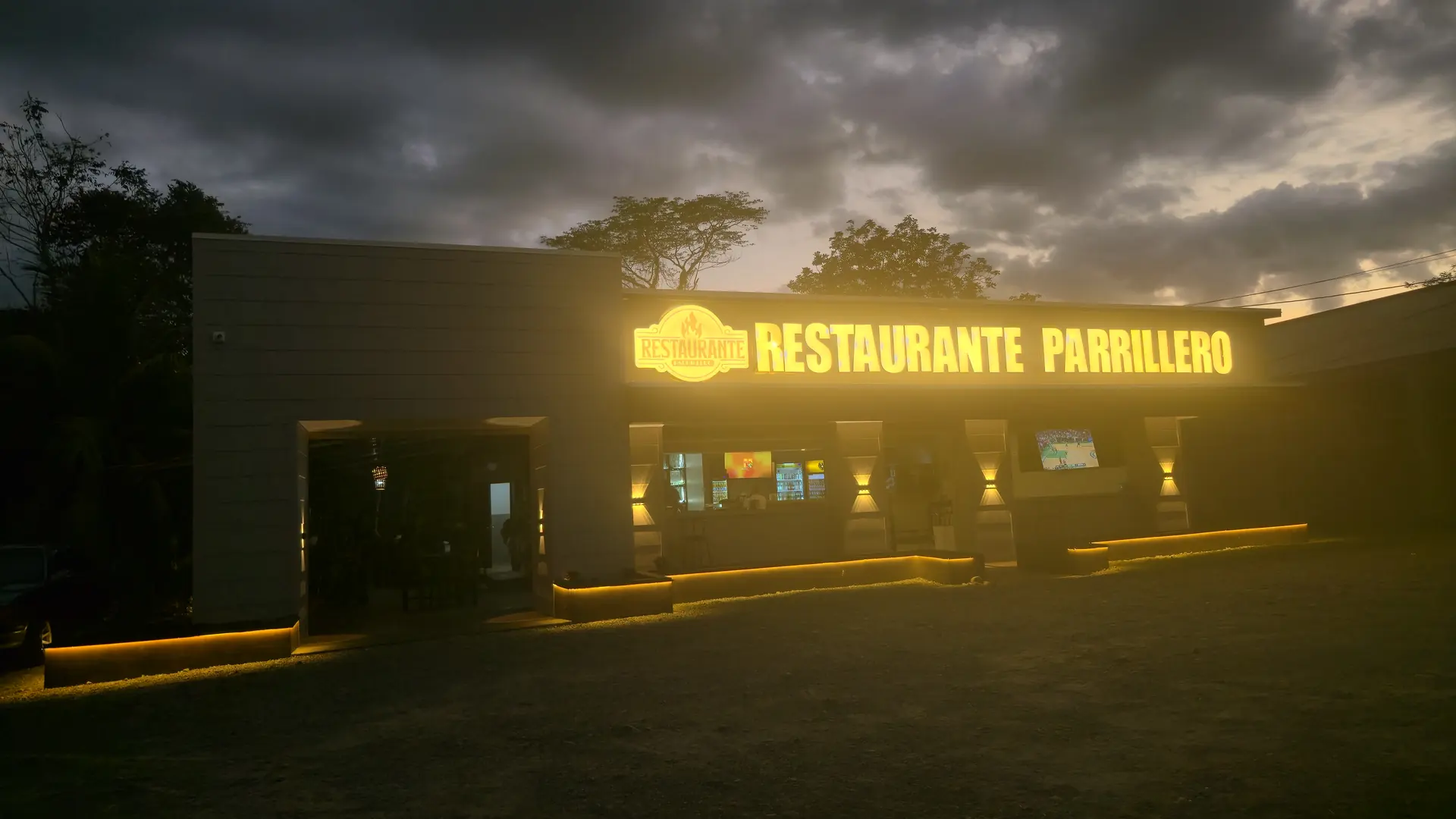 Letrero iluminado de Restaurante Parrillero al atardecer